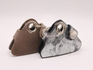 Zwei handgefertigte Leder-Markentäschchen für Hundemarken – Varianten in Braun und Schwarz-Silber nebeneinander