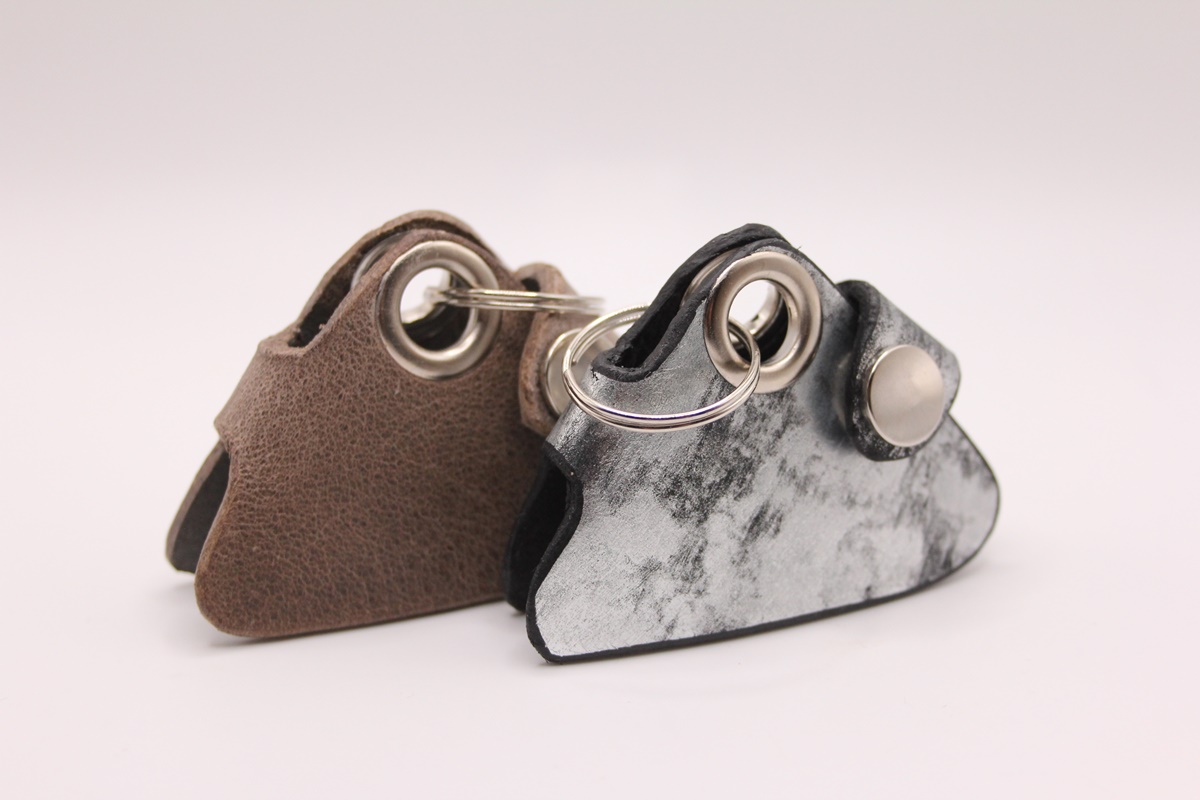 Zwei handgefertigte Leder-Markentäschchen für Hundemarken – Varianten in Braun und Schwarz-Silber nebeneinander